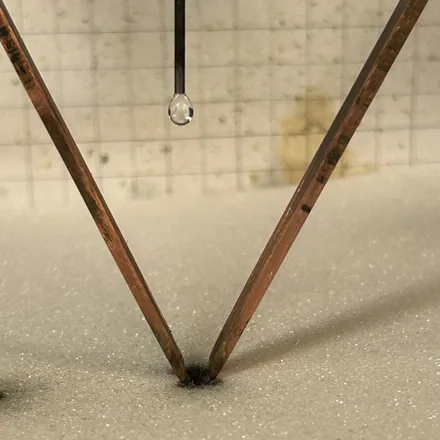 Electrolyte droplet suspended between comparative tracking index electrodes